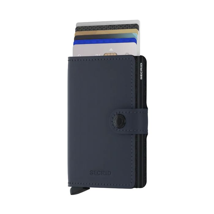 A navy blue Secrid minimalist cardholder wallet with a snap-button closure, shown standing upright with several credit cards partially inserted. The brand name 'SECRID' is embossed on the lower front and vertically on the side.