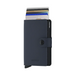 A navy blue Secrid minimalist cardholder wallet with a snap-button closure, shown standing upright with several credit cards partially inserted. The brand name 'SECRID' is embossed on the lower front and vertically on the side.