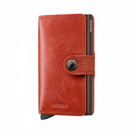 A red-orange textured leather wallet case with a dark brown metal cardholder and a snap-button strap closure, shown on a plain white background. The brand name 'SECRID' is embossed on the bottom and printed vertically on the side.