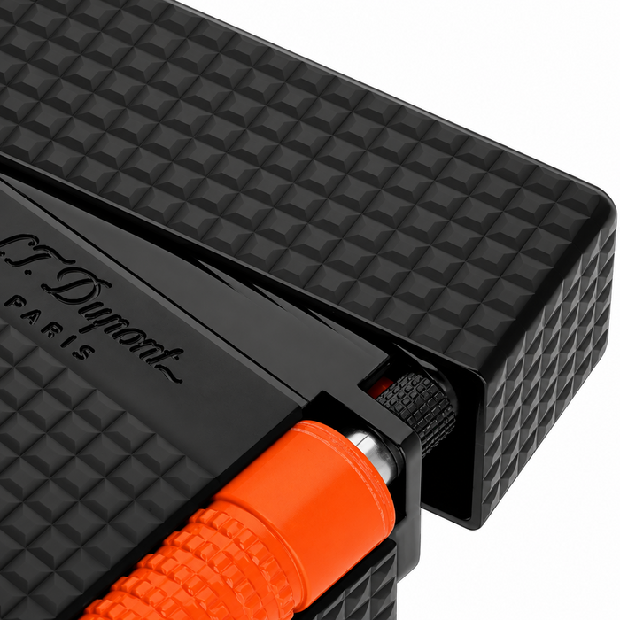 A close-up of a diamond-head guilloche pattern S. T. Dupont black lighter with a fluorescent orange striker. A luxury dual-flame lighter, perfect for cigar smoking. Model C23069