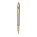 A sleek Sheaffer 100  Emily in Paris rollerball pen in a metallic champagne gold lacquer finish with champagne gold  trims and adorned with a bow-shaped emblem on the clip. Model E1937751